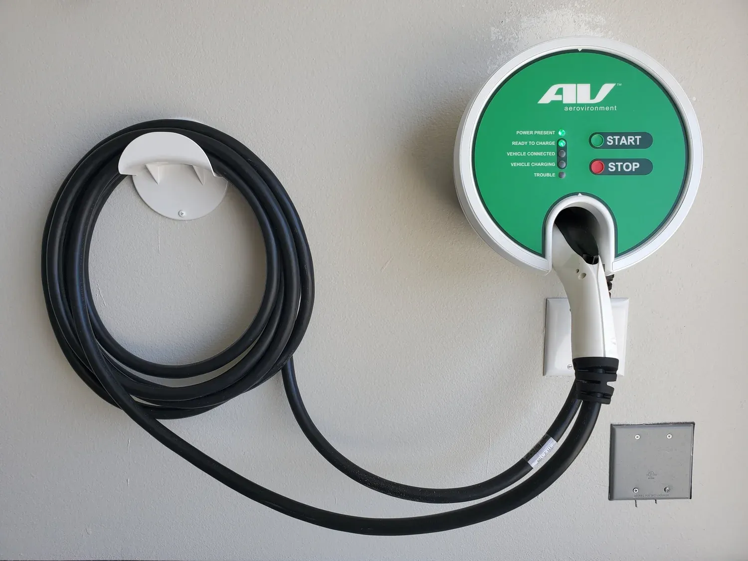 Wall-mounted EV charger with its cable coiled on the holster