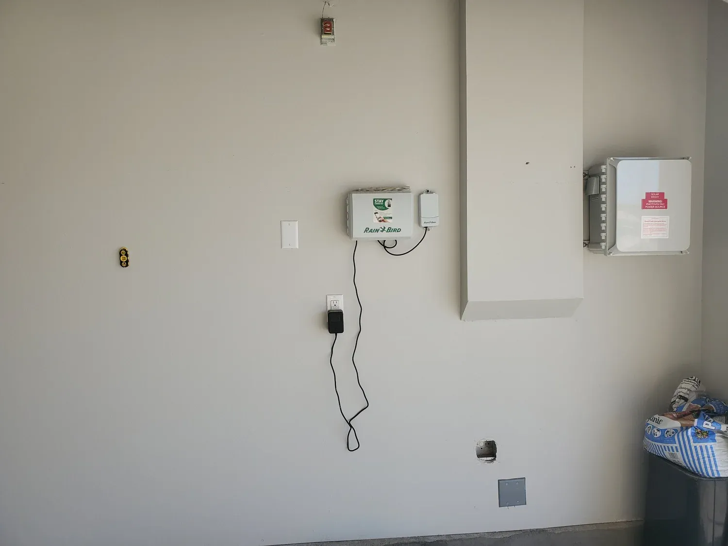 Garage wall with a new outlet and control box mounted during a service call