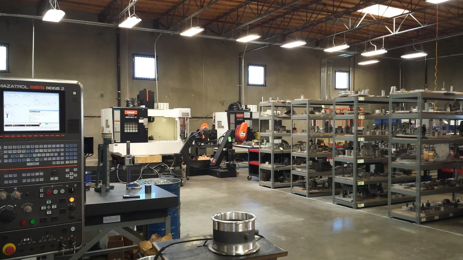 Machine shop floor with CNC machines and parts shelving under new lighting