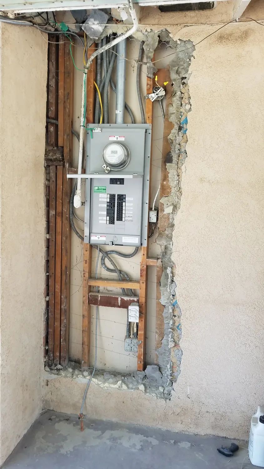 Residential panel and meter in an opened exterior wall during a panel replacement
